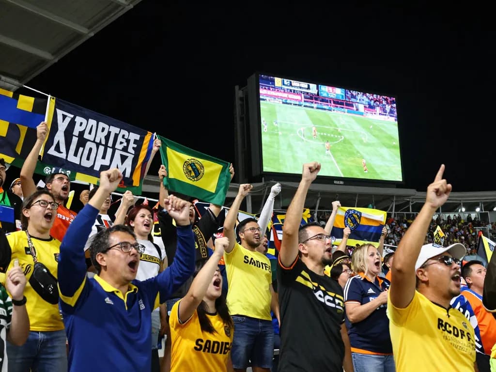 Xoilac fans cheering passionately during a live football match in a stadium.